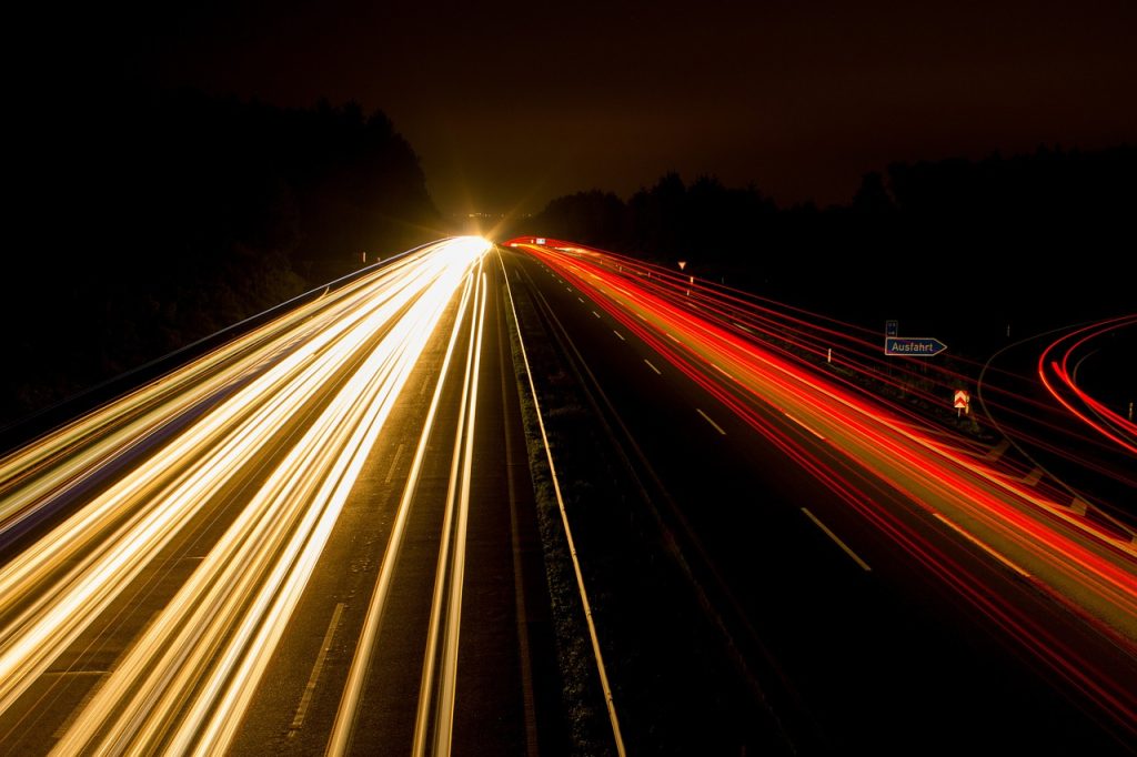 A long exposure photograph of a highway with streaks of headlights and taillights. 